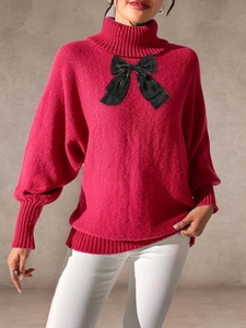 Detail of hot pink knit sweater featuring a large black bow and ribbed high neck design