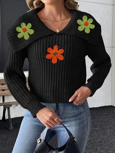 Close-up of black chunky knit sweater with vibrant crochet flower patches and large collar