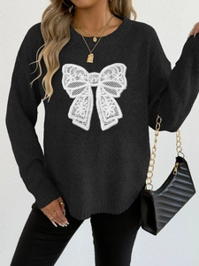 Detail of black knit sweater featuring a white lace butterfly applique and crew neckline