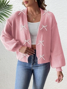 Detailed knit texture and white ribbon bow accents on this pink cardigan sweater