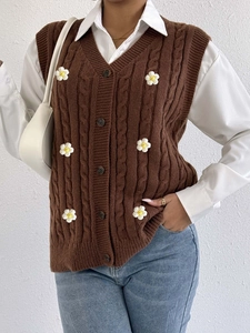 Detail of cable knit pattern and 3D daisy flowers on a brown V-neck vest cardigan