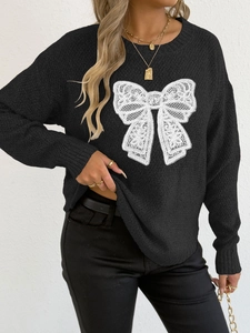 Detailed view of the white lace bow embroidery on black crewneck sweater