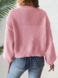 Detail of pink knitted cardigan featuring ribbed round neck and vertical knit texture