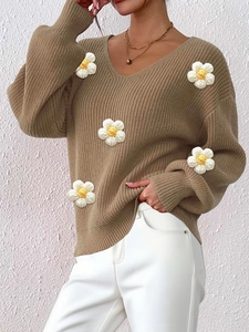 Close-up of knit sweater featuring 3D crochet flower appliques and ribbed V-neckline