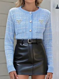 Detail der blauen Karo-Strickjacke mit Perlenknöpfen und silbernen Schleifen-Akzenten