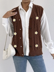 Detailed close-up of brown knit vest featuring white 3D floral patches and cable textures