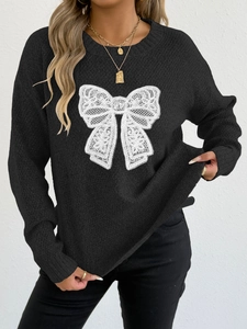 Detailed view of the white lace butterfly embroidery on a black knit sweater