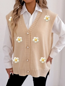 Close-up of beige knitted vest with pearl buttons and white daisy floral embroidery patches