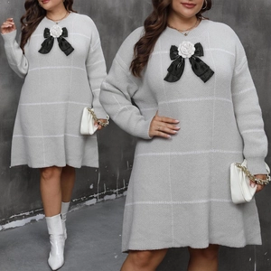 Detail eines grau gestreiften Strickkleids mit weißer Kamelie und schwarzer Schleife