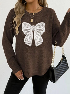 Detailed view of the white lace butterfly applique on a dark brown knitted sweater