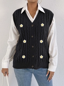 Detail of black cable-knit cardigan vest with V-neck and 3D white flower embroidery