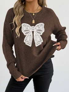 Detail of a brown knit sweater featuring intricate white lace butterfly embroidery on chest