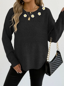 Dettaglio di applicazioni floreali all'uncinetto su maglione nero in maglia a maniche lunghe