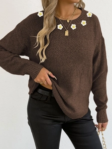 Dettaglio di margherite all'uncinetto su maglione a maglia marrone scuro da donna