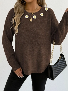 Dettaglio del maglione marrone scuro con margherite all'uncinetto e morbida trama a maglia