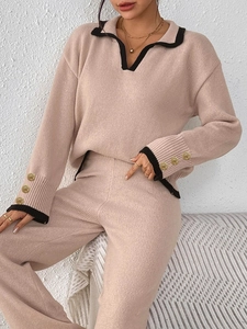 Detail of female pink knit sweater showing black collar and gold buttons on cuffs