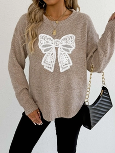 Detailed close-up of white lace butterfly embroidery on light brown knitted sweater