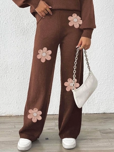 Close-up of brown knit wide-leg pants with pink floral embroidery and beadwork details