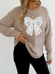 Detailed view of brown knit sweater featuring white lace butterfly applique on the chest