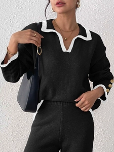 Detail of elegant gold relief buttons on contrast white cuffs of a black knit sweater