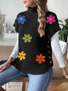 Detail showing colorful crochet floral patches and side buttons on black knit vest