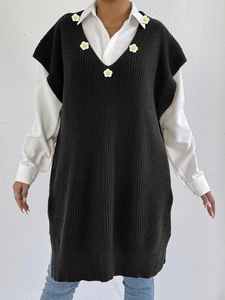 Close-up of black knit V-neck vest dress with delicate white daisy floral patchwork