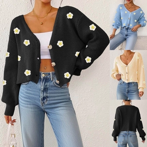 Detail der Strickjacke mit V-Ausschnitt, Bernstein-Knöpfen und Gänseblümchen-Stickerei