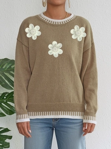 Detail view of 3D white flower embroidery and beads on khaki knitted sweater