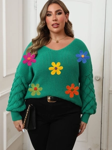 Detail of green V-neck sweater with colorful handmade crochet flowers and puff sleeves