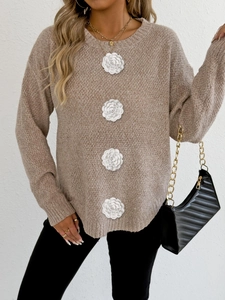 Détail d'un pull en maille beige avec appliques de fleurs blanches en crochet en relief
