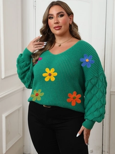 Detailed view of 3D colorful floral embroidery and openwork knit on a green V-neck sweater