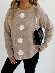 Détail du pull en maille avoine avec décorations de fleurs blanches au crochet en relief