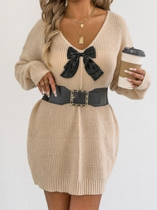 Detailed close-up of a V-neck knitted dress featuring a stylish black satin bow accent