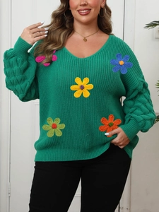 Detail of green V-neck sweater featuring 3D handmade crochet flowers and knit texture