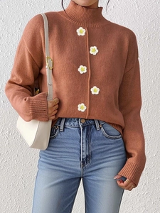 Detalle de jersey de cuello alto caramelo con flores tejidas en 3D blancas decorativas