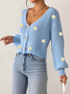 Nahaufnahme hellblaue Strickjacke mit 3D-Blütenapplikationen und großen weißen Knöpfen