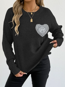 Detalle de encaje blanco en forma de corazón sobre el suéter negro de punto