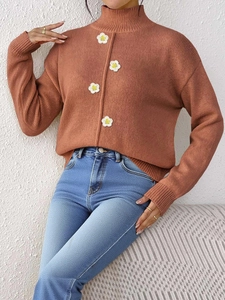 Detalle de jersey de cuello alto rojo óxido con aplicaciones de flores de ganchillo y punto