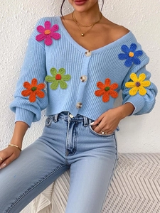 Détail de la broderie de fleurs colorées en 3D sur le gilet en maille bleu clair