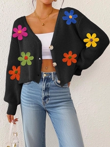 Détail de fleurs crochetées en 3D colorées sur un gilet en maille noire pour femme
