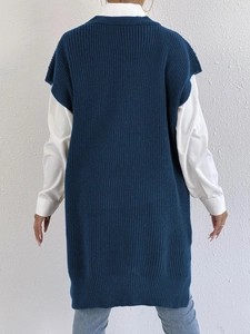 Rear view of long navy blue chunky knit vest styled over a white shirt and jeans