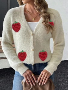 Détail de broderies fraises et boutons perles sur un cardigan crème en fausse fourrure