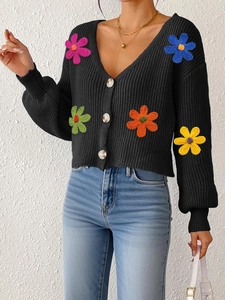 Gros plan détaillé des patchs de fleurs colorées en crochet sur cardigan noir