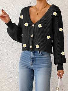 Detail der schwarzen Strickjacke mit weißen 3D-Gänseblümchen-Stickereien und Knöpfen