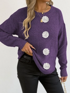 Détail de fleurs roses 3D crochetées sur un pull en maille violet à manches longues