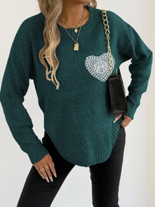 Detalle de jersey de punto verde oscuro con parche de corazón de encaje blanco bordado