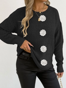 Détail de fleurs au crochet 3D blanches sur un pull en tricot noir à manches longues