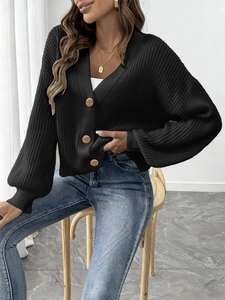 Detail of black knit cardigan featuring elegant gold round buttons and ribbed cuffs