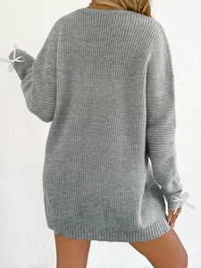 Rear view of grey oversized knit dress featuring delicate ribbon bows on the cuffs