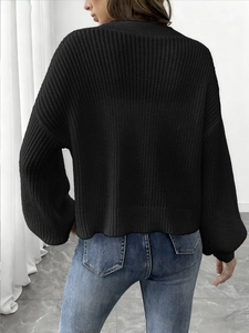 Back view of a black waffle-knit cardigan featuring drop shoulders and a relaxed fit design